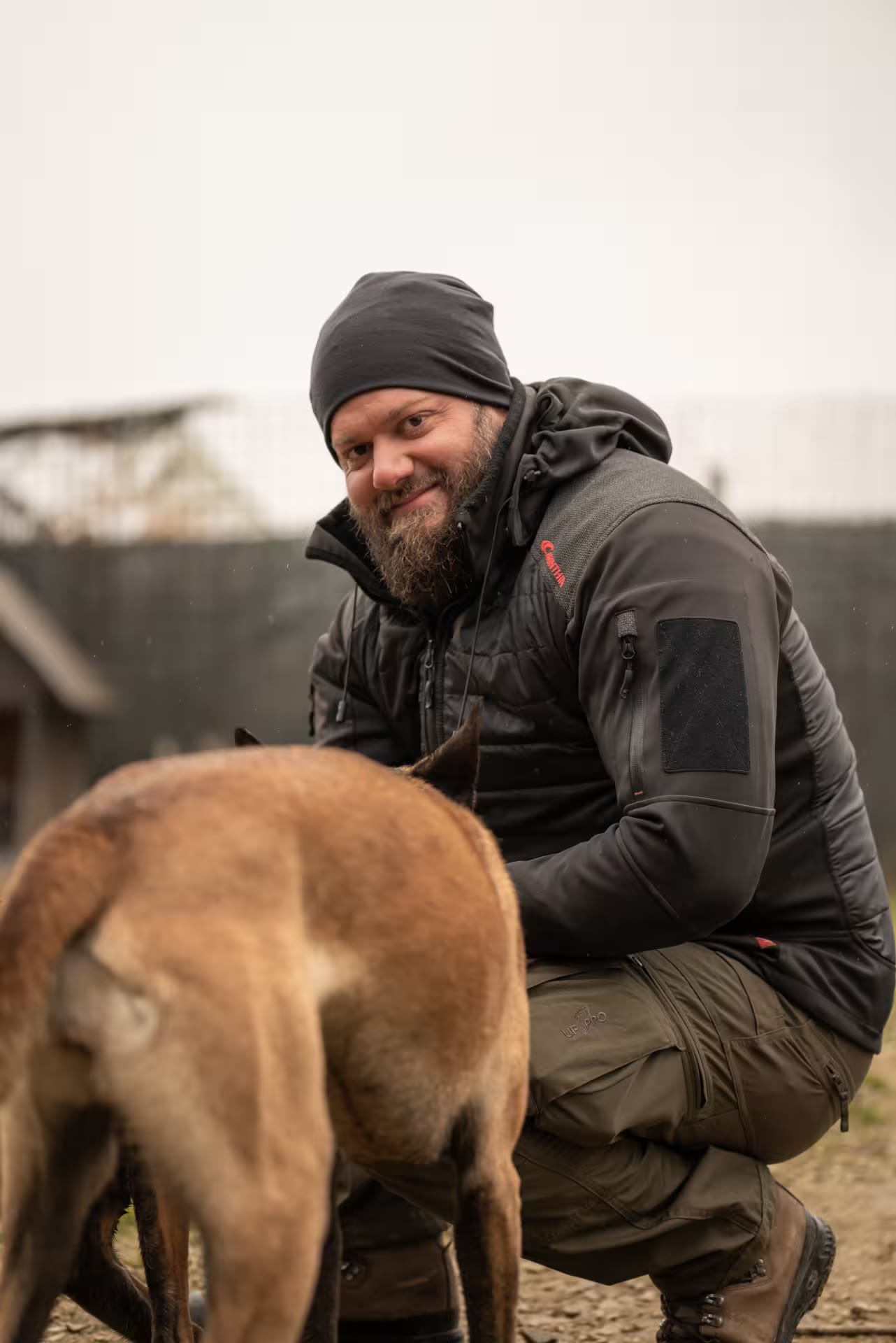 Georg Resch kniet lächelnd neben einem Hund auf dem Vereinsgelände